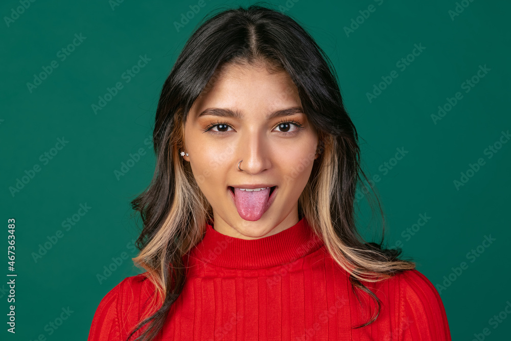 Fototapeta premium Close-up portrait of young beuatiful girl, student in bright red sweater isolated on green studio backgroud.