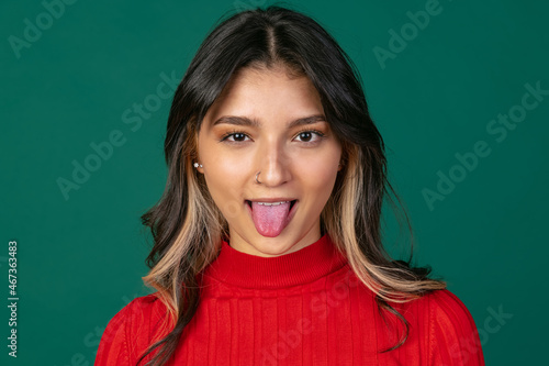 Close-up portrait of young beuatiful girl, student in bright red sweater isolated on green studio backgroud.