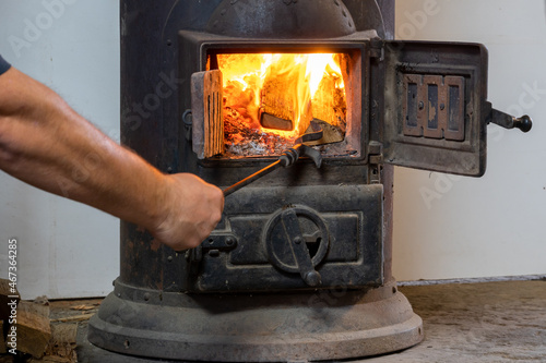 Fire in an old stove. Furnace of the stove in the house. Lighting a fire in a stove. Human hand throws up wood burning fire. Warming warmth. A stove with open door in the house.