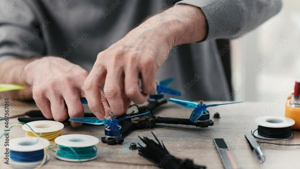 Man engineer screws propeller with nut during quadcopter repairing process. Closeup view Man engineer screws propeller with nut during quadcopter repairing process. Closeup view