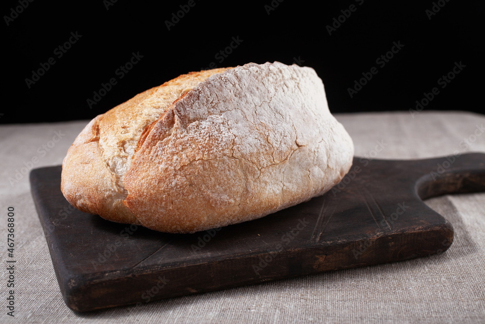 ciabatta of wheat flour on a tree stand close-up on a black background. Baking, flour, bread ciabatta of wheat flour on a tree stand close-up on a black background. Baking, flour, bread