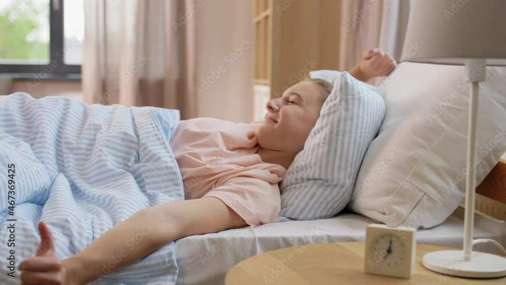 people, bedtime and rest concept - sleepy girl with alarm clock awaking in bed at home people, bedtime and rest concept - sleepy girl with alarm clock awaking in bed at home