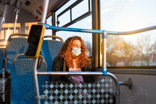 Young woman with respiratory mask traveling in the public transport by bus