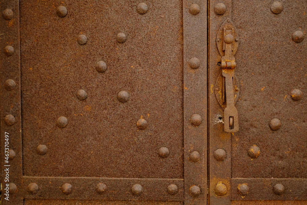 Rusted iron. Iron door with studs and lock.Rusted iron sheet of an ancient door. 