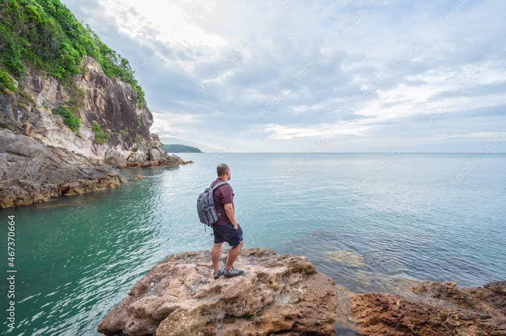 Asian backpacker looking to endless horizon on the rocky coast at Pha Suk Nirun cliff chathaburi thailand.Pha Suk Nirun cliff A popular sunrise and sunset location in chathaburi city.