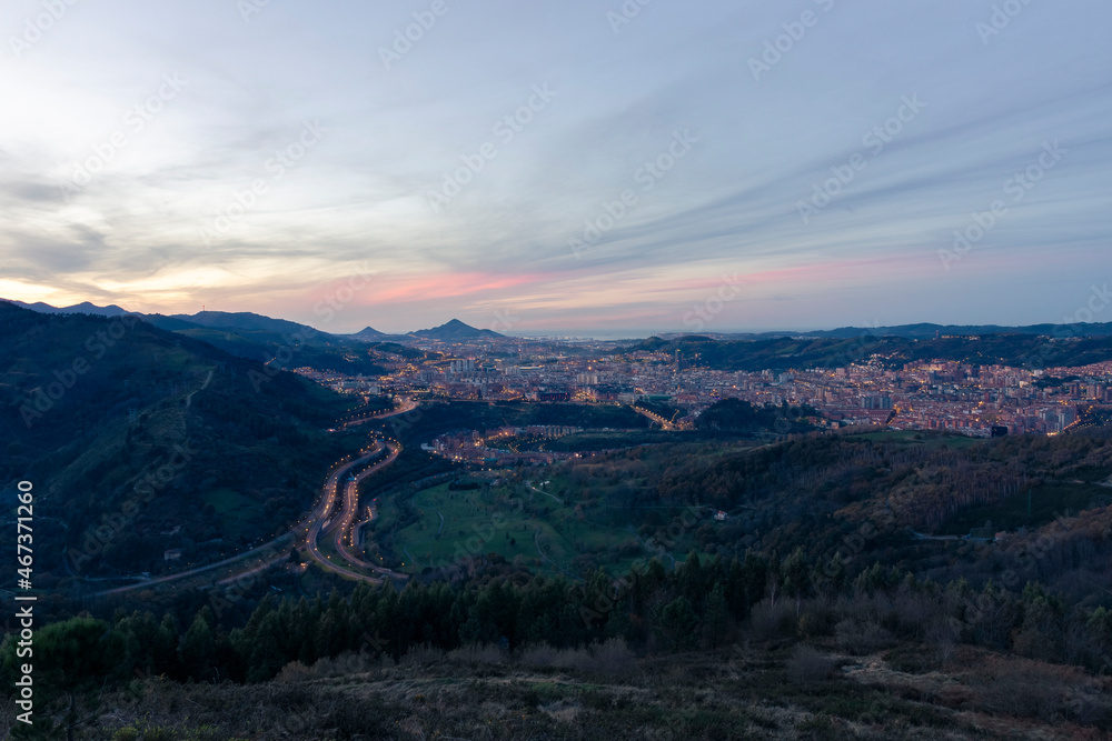 view of the city of Bilbao at sunset from a nearby mountain
