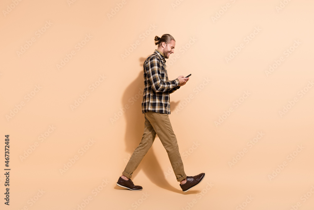 Fototapeta premium Full body profile side photo of young guy look typing message blogger walk isolated over beige color background