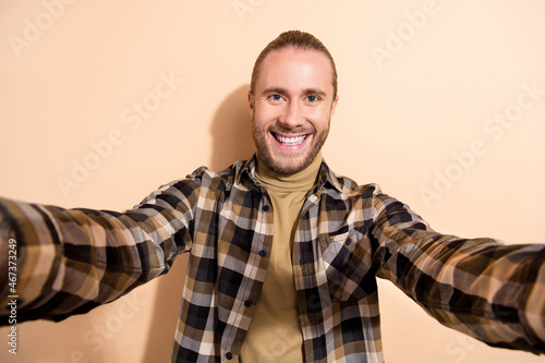 Photo of young cheerful man take selfie enjoy vacation vlogging isolated over beige color background