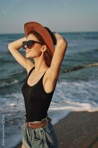 cheerful woman in sunglasses and a hat by the ocean walk summer