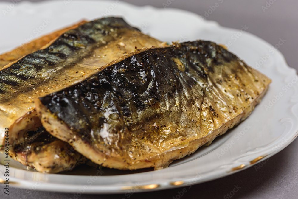 Fried mackerel with a short body file or Platoo in Thai is served on a white porcelain plate on a gray background. Popular fish menu in Thailand. (close-up, side view) Fried mackerel with a short body file or Platoo in Thai is served on a white porcelain plate on a gray background. Popular fish menu in Thailand. (close-up, side view)