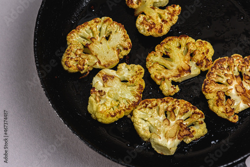 Vegetarian food. Grilled cauliflower steak on a cast iron skillet, top view, close-up view.