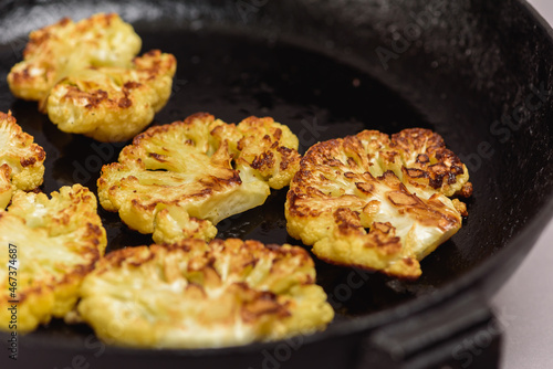 Vegetarian food. Grilled cauliflower steak on a cast iron skillet, top view, close-up view.