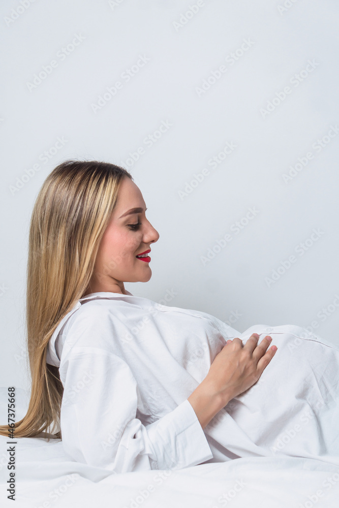 Positive pregnant woman with hand on belly lying down on bed Positive pregnant woman with hand on belly lying down on bed