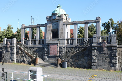 An old pier with a clock on the Vltava embankment in Prague against the blue sky on a sunny day