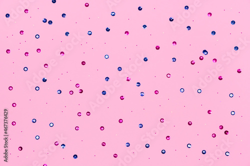 Pink background with colored sequins and shiny sequins. Suitable for backdrop for your design. Top view, copy space. Template.
