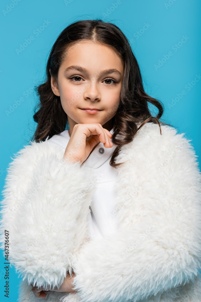 preteen girl in white faux fur jacket looking at camera isolated on blue. preteen girl in white faux fur jacket looking at camera isolated on blue.