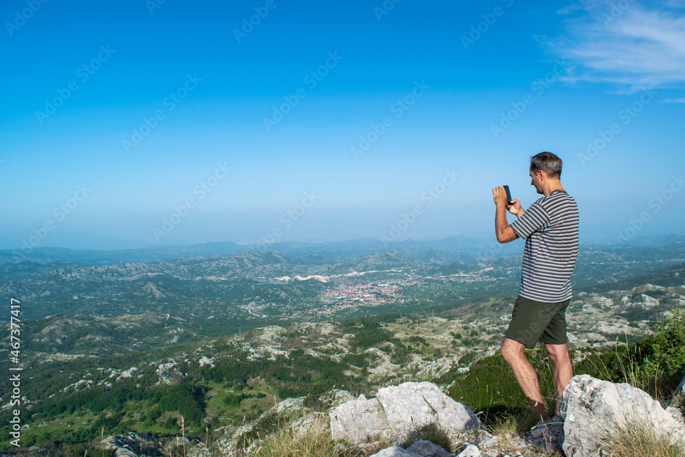 Tourist man on viewpoint at top of Jezerski mountain, near Njegos mausoleum at Cetinje city background. Lovcen National Park. Montenegro.