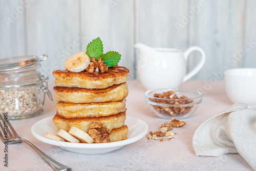 Breakfast with pancakes with banana, nuts and mint on a light background.