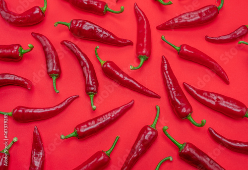Seamless pattern done of red chilli peppers isolated on red background.