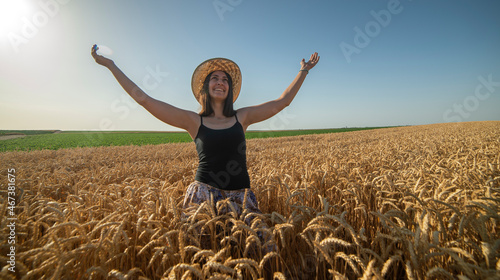 Happy woman in straw hat standing on yellow farm meadow © Vesna