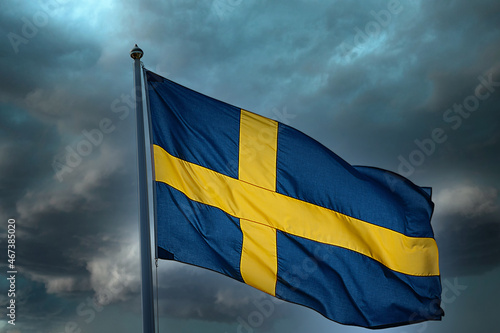 A national flag of Sweden against a sky with storm clouds.