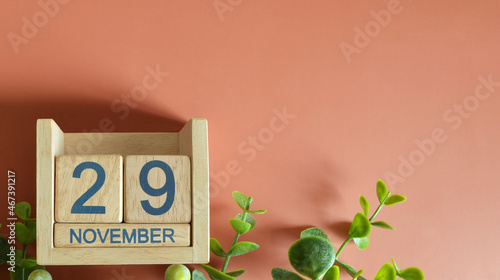 November 29, Date design with calendar cube and leaf on orange background.