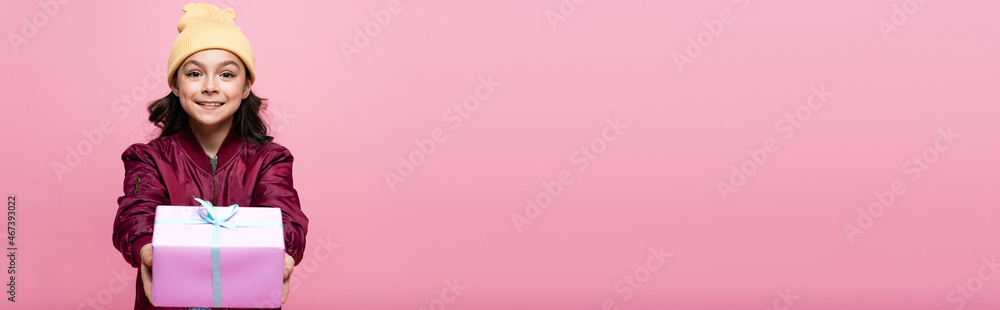 joyful preteen girl in trendy outfit holding wrapped present isolated on pink, banner. joyful preteen girl in trendy outfit holding wrapped present isolated on pink, banner.