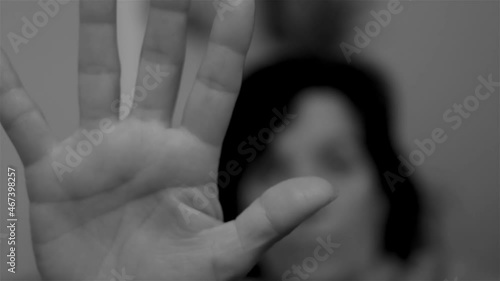 Black and white video of a woman extends her open hand as a sign to stop sexist violence photo
