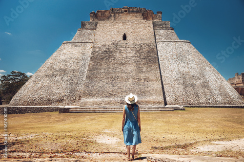 A young woman stands against the backdrop of the Mayan pyramid in Uxmal and enjoys the breathtaking view, from the back. Pyramid of in the ruins of Uxmal, Yucatan, Mexico,Unesco archaeological site