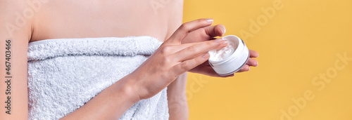 Closeup shot of hands applying moisturizer. Beauty woman holding a glass jar of skin cream.