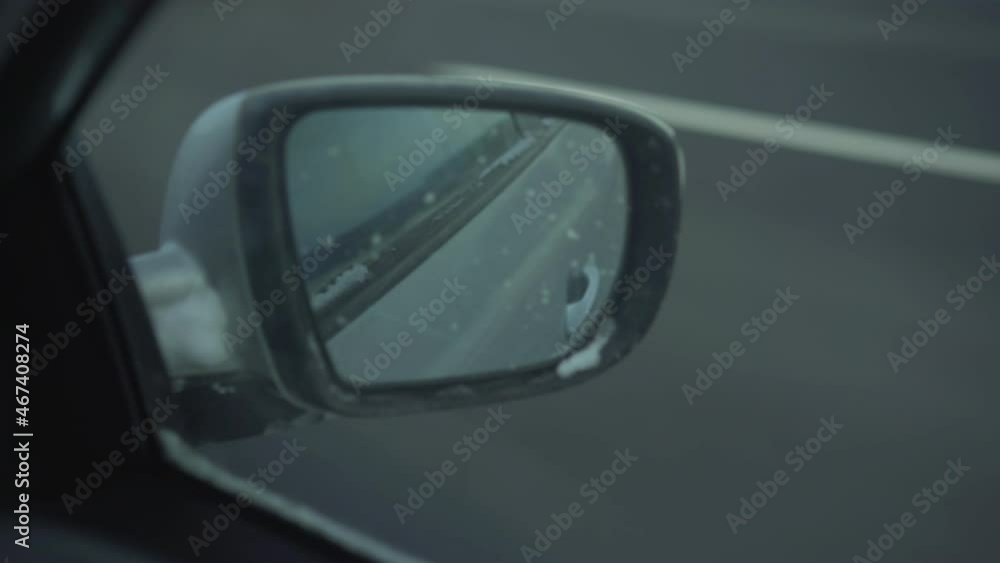 Car with dirty side view mirror driving fast on highway at winter season in bad weather Car with dirty side view mirror driving fast on highway at winter season in bad weather