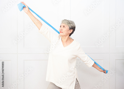 Senior asian woman doing exercises with resistance band at home.