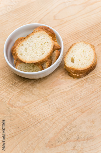 white stoneware bowl with fresh organic sliced bread on a rustic wooden background