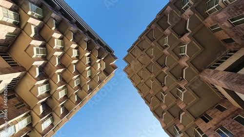 Billede på lærred Upside view to the blue sky through geometric architecture, abstract urban background