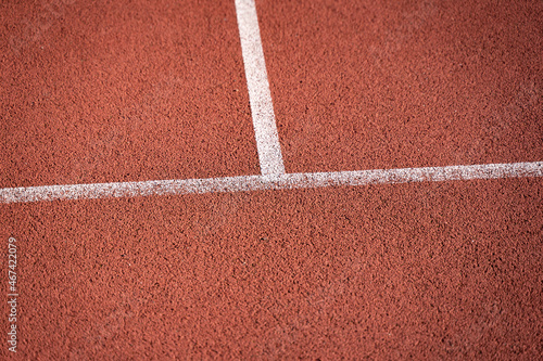 Rubber playground of an outdoor basketball court. White lines on a red synthetic material. A damping polymer is used for the ground material of the sports field.