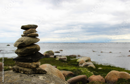 Pyramid made by stones. Stone tower and sea in the background. Stone pile was made by tourist in coastline. Rocks on the coast of the Sea. Beautiful seascape. Concept of balance, harmony and vacation.