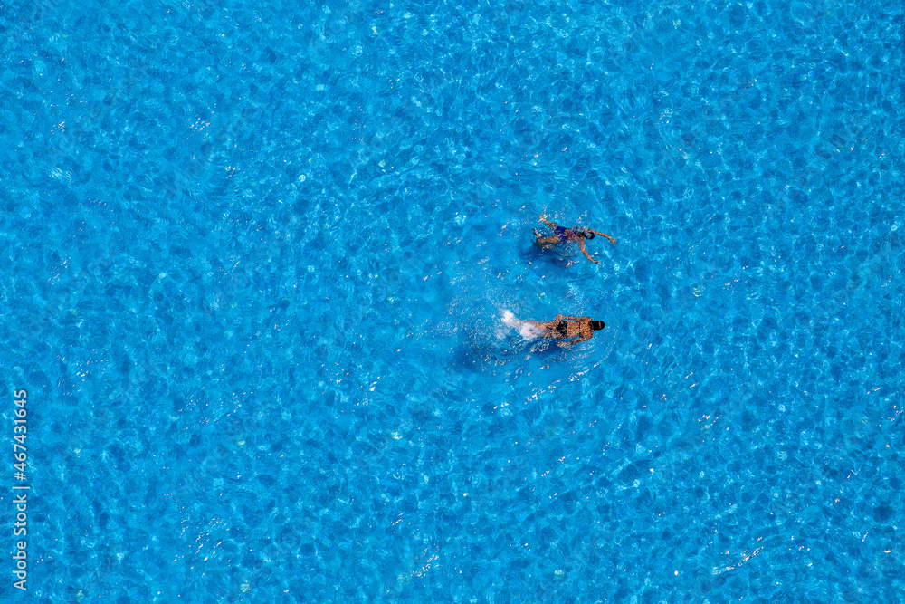 Two young girls swims in the swimming pool, view from above