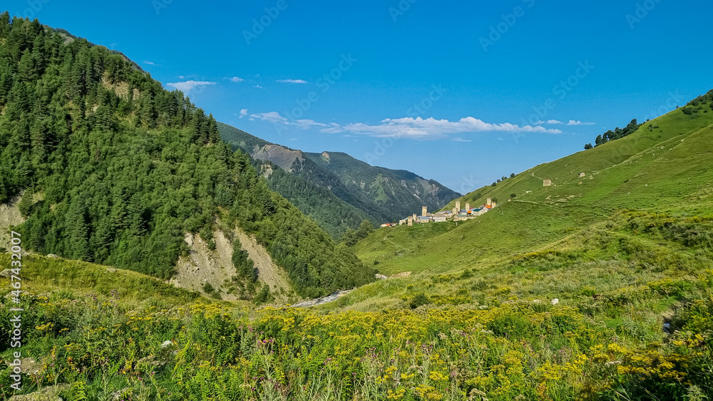 Panoramic view on Adishi,a mountain village,located in the High Caucasus,Svaneti Region in Georgia.The Svan watch towers are behind the lush green hills,where cows are grazing. Hiking trail,Solitude.