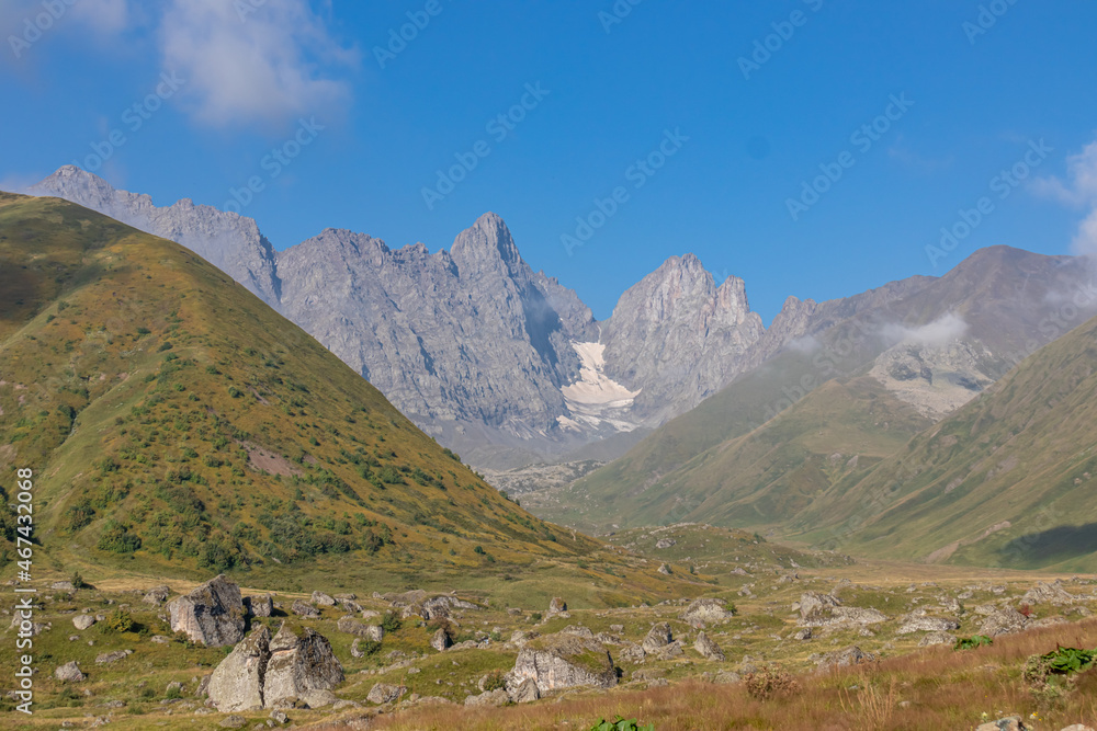 A panoramic view on the sharp mountain peaks of the Chaukhi massif in the Greater Caucasus Mountain Range in Georgia, Kazbegi Region. The valley is full of the Roshka stones. Georgian Dolimites.