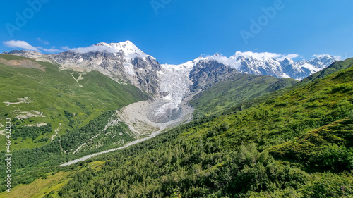A panoramic view on the snow-capped peaks of Tetnuldi  Gistola  Lakutsia and the Adishi Glacier in the Greater Caucasus Mountain Range in Georgia  Svaneti Region. Sharp peaks  wanderlust  solitude.