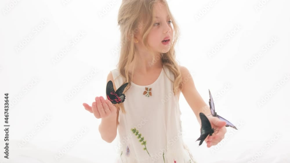 Beautiful little girl in a dress in the studio on a white background plays with real big butterflies. Beautiful little girl in a dress in the studio on a white background plays with real big butterflies.