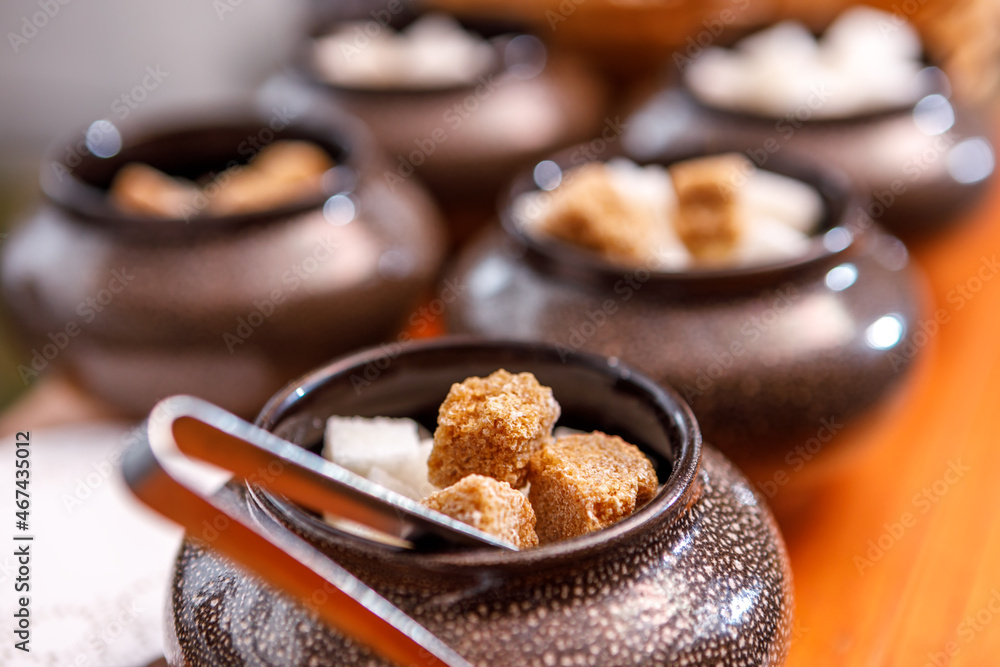 A sugar bowl with tongs filled with fruit sugar is on the table. A sugar bowl with tongs filled with fruit sugar is on the table.