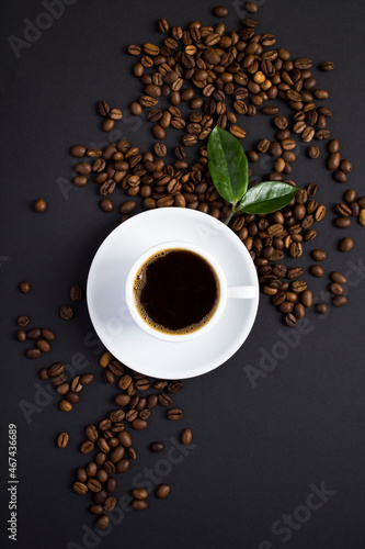 Top view of coffee cup and coffee beans on the black background. Close-up. Location vertical.