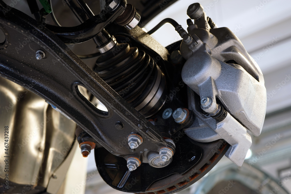 Close-up shows the suspension arm of a modern car in place of the connection with a ball joint and a brake caliper. Selected focus. Car service and auto parts. Close-up shows the suspension arm of a modern car in place of the connection with a ball joint and a brake caliper. Selected focus. Car service and auto parts.