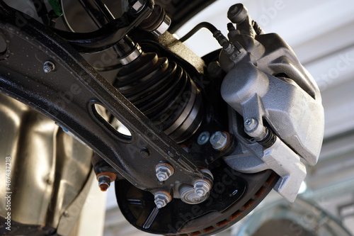 Close-up shows the suspension arm of a modern car in place of the connection with a ball joint and a brake caliper. Selected focus. Car service and auto parts. © Орлов Александр