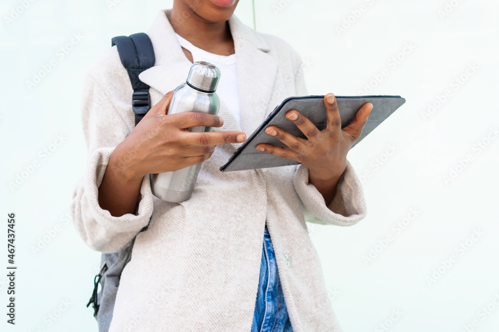 Faceless crop woman with thermos browsing tablet Faceless crop woman with thermos browsing tablet