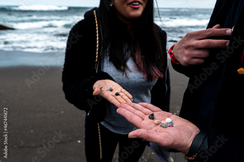 Young woman and man sharing the shells they found on the seashore at pichilemu's infiernillo beach.