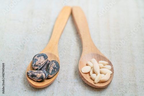 shelled and whole pine nuts in spoon on the wooden background with copy space