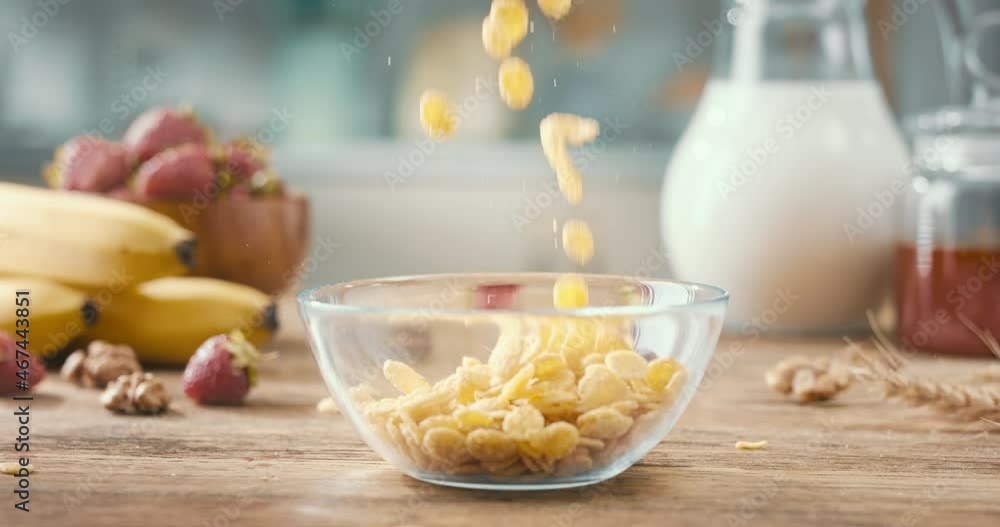 Close up of crusty corn flakes falling in glass bowl. Corn cereal filling plate on breakfast table. Muesli as balanced vegetarian breakfast 4k footage Close up of crusty corn flakes falling in glass bowl. Corn cereal filling plate on breakfast table. Muesli as balanced vegetarian breakfast 4k footage