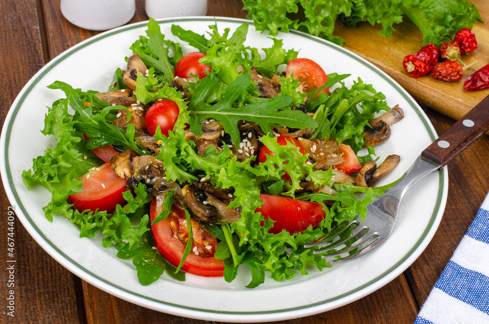 Diet salad of arugula leaves, tomatoes and fried mushrooms on wooden table. Studio Photo Diet salad of arugula leaves, tomatoes and fried mushrooms on wooden table. Studio Photo